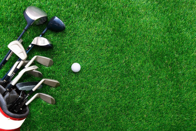Golf ball and golf club in bag on green grass