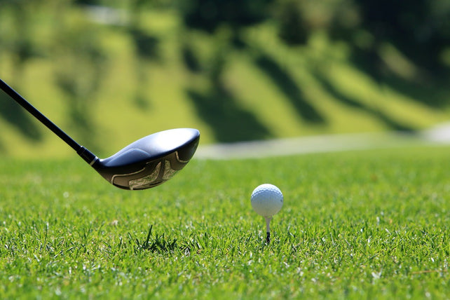 golf club about to swing at a golf ball on a tee