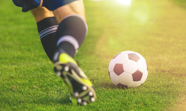 man in cleats kicking soccer ball