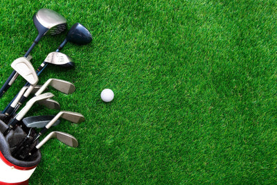 Golf ball and golf club in bag on green grass