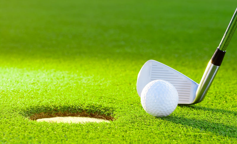 golf ball from the hole with the putter on golf turf