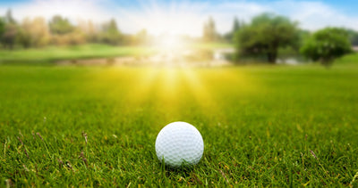 golf ball on green grass with sunrise sunset