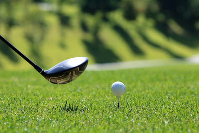 golf club about to swing at a golf ball on a tee