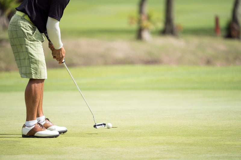 Golfer gently putting golf ball straight to the hole