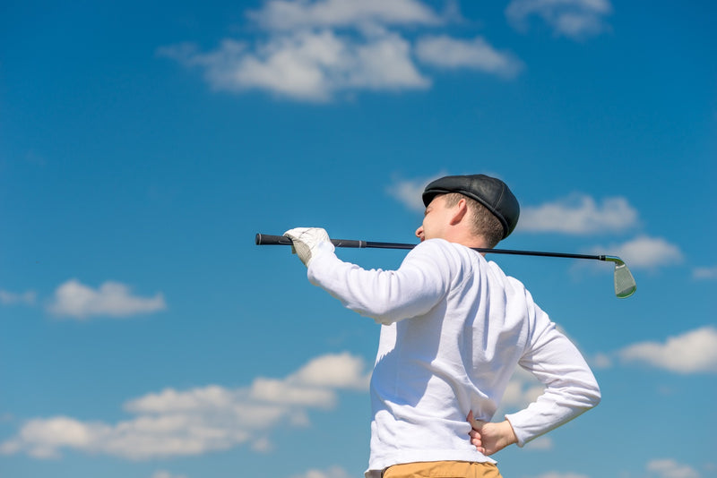 Golfer with a golf club rubs a sick back on the field