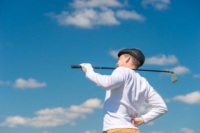 Golfer with a golf club rubs a sick back on the field