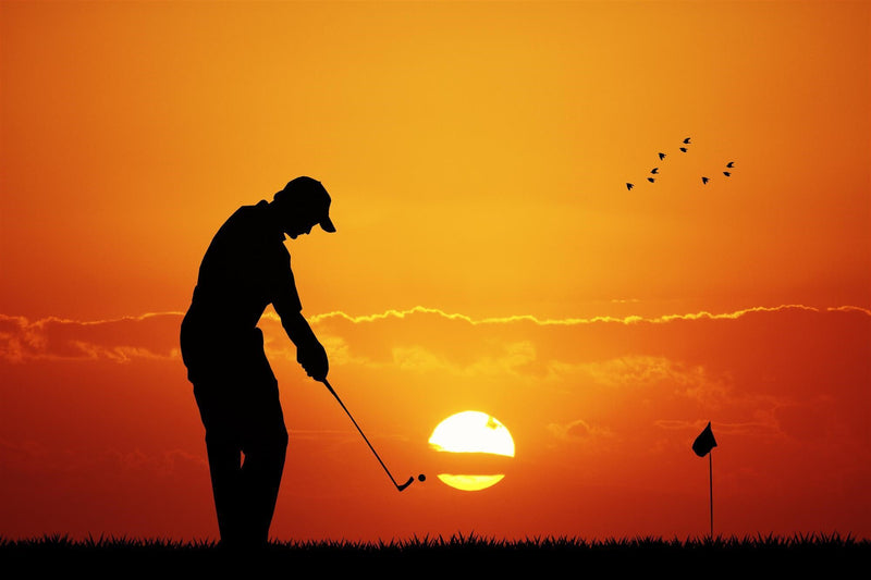 Golfer hitting iron at sunset