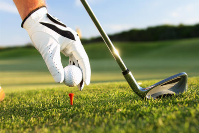 Golfer setting ball on tee for iron shot