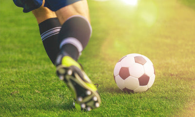man in cleats kicking soccer ball