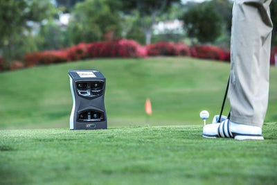 A golf launch monitor set up outdoor to analyse swings.