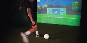 Athlete kicking soccer ball into simulator screen