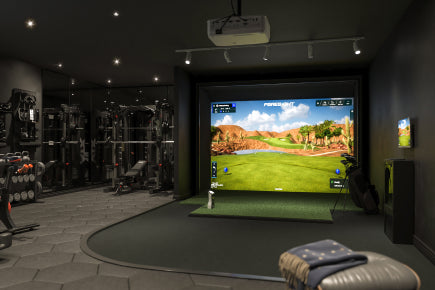 A room with a golf simulator on the wall